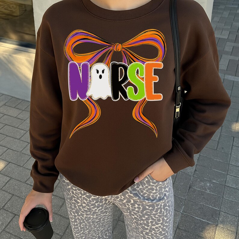 May include: A brown sweatshirt with a colorful bow design and the word "NURSE" in purple, white, green, and orange letters. The white letter "R" is a ghost. The sweatshirt is part of a Halloween theme.