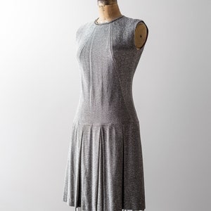 May include: A silver and gray sleeveless dress with a pleated skirt on a dress form.