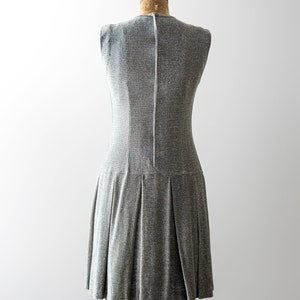 May include: A silver sleeveless dress with a pleated skirt on a dress form.