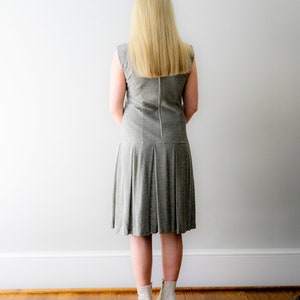 May include: A woman wearing a silver sequined dress with a pleated skirt and white ankle boots.
