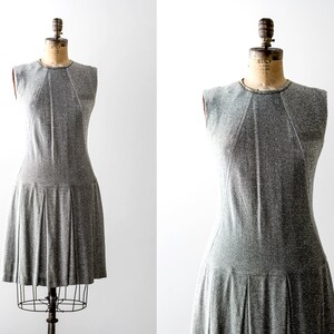 May include: A sleeveless gray dress with a pleated skirt. The dress is on a mannequin.