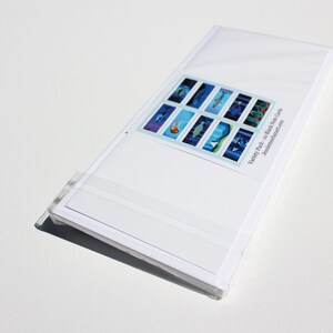 May include: A pack of 10 blank water color cards with a variety of underwater scenes. The cards are white with a blue and white design. The text on the back of the cards reads "Variety Pack - 10 blank Water Cards, JessicasDreamArt.com".