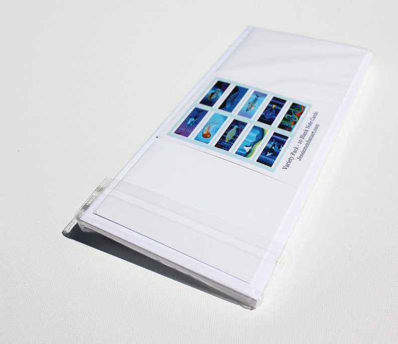 May include: A pack of 10 blank water color cards with a variety of underwater scenes. The cards are white with a blue and white design. The text on the back of the cards reads "Variety Pack - 10 blank Water Cards, JessicasDreamArt.com".