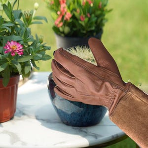 Leather gloves with engraved cuff shown folded on wooden background