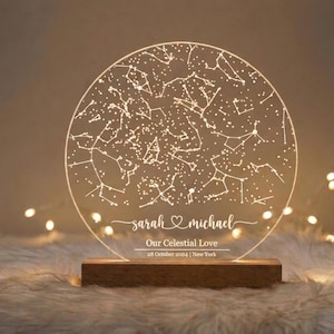 May include: A circular, illuminated acrylic night light displaying a constellation map. The light sits on a wooden base and features the names "sarah & michael", the text "Our Celestial Love" and the date "28 October 2024 | New York".