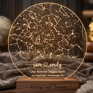 May include: An illuminated acrylic night light with a constellation design. The light is mounted on a wooden base engraved with "Always and Forever." The text "sam & emily" and "Our forever began here" are also visible.