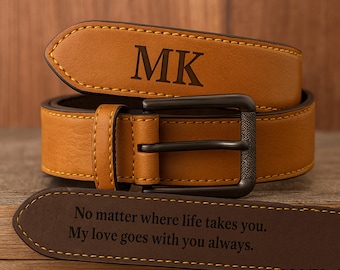 May include: A tan leather belt with a dark metal buckle. The belt is engraved with the initials "MK" and the message "No matter where life takes you. My love goes with you always."