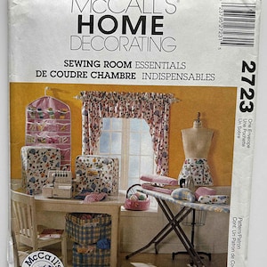 May include: A McCall's Home Decorating sewing pattern envelope. The image shows a sewing room scene with a table, sewing machine, ironing board, and various sewing accessories. The text on the envelope reads "Sewing Room Essentials."