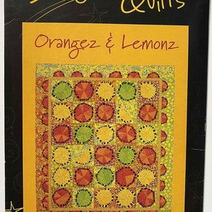 May include: A quilt pattern featuring a colorful design of orange, yellow, and green circles with black outlines. The pattern is titled "Orangez & Lemonz" and is from Stargazey Quilts.