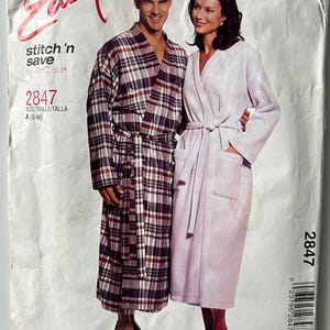 May include: A sewing pattern package featuring a man and woman wearing robes. The man's robe is a plaid pattern in shades of burgundy, navy, and white. The woman's robe is a solid light purple. The package has the word "Easy" in red script.