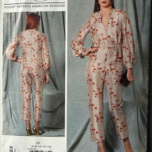 May include: A Vogue Patterns American Designer sewing pattern featuring a jumpsuit design. The jumpsuit is beige with a red floral pattern, long sleeves, and a belt. The pattern includes sizes 6-8-10-12-14. The brand name "Rachel Comey" is visible.
