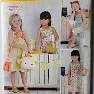 May include: Simplicity sewing pattern 8145 for girls' dresses, sizes 3-8. The pattern features multiple dress styles, including a polka dot dress and a floral dress. The image includes the text "lemonade for sale" and "cookies 50¢".
