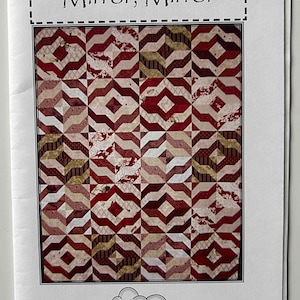 May include: A quilting pattern booklet with a red, white, and gold geometric design. The title of the pattern is "Mirror, Mirror" and the booklet is from "A Quilter's Dream".