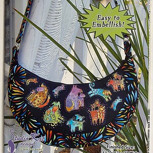 May include: A colorful fabric bag with a black background and a variety of animal designs. The bag is shaped like a crescent moon and has a strap. The bag is 11 inches long, 6 inches wide, and 3 inches deep. The text on the image reads "the mezza luna" and "Easy to Embellish!"