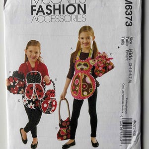 May include: McCall's Fashion Accessories pattern for kids' aprons and matching bags. The pattern features various apron and bag designs, including ladybug and floral patterns. The size range is for kids aged 3-8 years old.