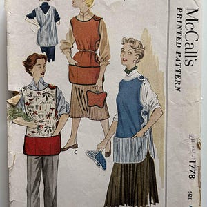 May include: A vintage McCall's printed pattern envelope for a Misses' Shirt-Tail Cobbler Apron, pattern number 1778, size medium. The cover features illustrations of three apron variations in red, blue, and white with floral and striped patterns.