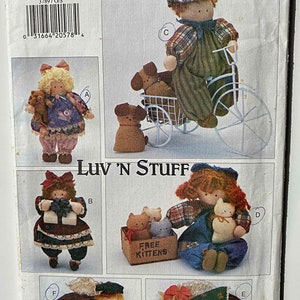 May include: A sewing pattern for making five different dolls. The dolls are dressed in various outfits and have different accessories, including a bicycle, a basket of kittens, and a gift box. The pattern is from Butterick and is called "Luv 'N Stuff".