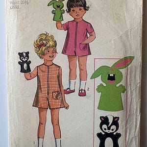 May include: Vintage Simplicity sewing pattern 8763 for children's clothing. The pattern includes instructions for a pink romper and a checkered romper. The pattern also includes transfers for puppet designs, including a green bunny and a black and white skunk.