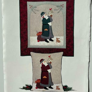 May include: A printed pattern featuring Santa Claus holding a birdhouse. The design includes a framed quilt and a pillow with the same image. The text "SANTA WITH BIRDHOUSE" is at the top. The pattern is from the "Olde Santa Series".