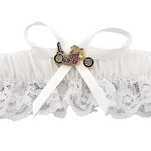 May include: White lace garter with a decorative motorcycle charm. The garter features a white satin bow and a motorcycle charm with red, black, and gold accents. The lace trim adds a delicate touch to the design.