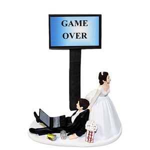 May include: A wedding cake topper featuring a bride in a white dress and a groom in a black suit, with a laptop and cans. A sign above reads "GAME OVER". A popcorn bucket is also included.