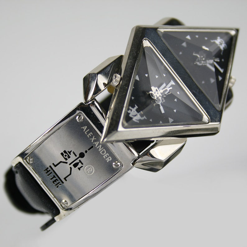 Pu&ograve; includere: Un orologio da polso argento e nero con un quadrante triangolare e un cinturino in pelle nera. Il quadrante dell'orologio ha un design argentato e il cinturino ha il testo "ALEXANDER HI-TEK" e un simbolo di marchio registrato.