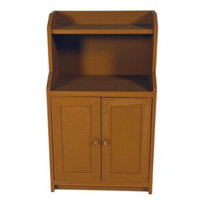 Peut inclure: Un petit meuble marron avec deux portes et une étagère. Les portes présentent un motif diagonal texturé. Le meuble possède une petite étagère au-dessus des portes et une garniture décorative sur le dessus. Le meuble est en matériau solide.