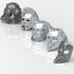 May include: Five silver and gray masks with different designs. The masks are arranged in a row from left to right. The masks are all made of metal and have a shiny finish.