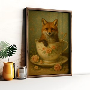 Könnte beinhalten: Gerahmter Kunstdruck mit einem Fuchs in einer Teetasse. Die Teetasse ist mit rosa Rosen und goldenen Verzierungen verziert. Der Fuchs hat rotbraunes Fell und blickt nach vorne. Der Hintergrund zeigt ein grünes Blumenmuster.