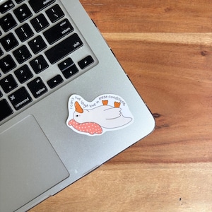 May include: A white sticker featuring a cartoon goose with orange beak and feet, lying on its back. The goose rests on a pink pillow with white polka dots. Text on the sticker reads "I can't live, laugh, love in these conditions."