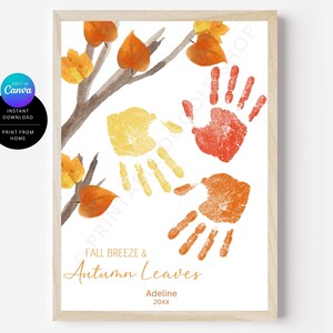 Puede incluir: Una impresión enmarcada con una ilustración en acuarela de una rama de árbol con hojas naranjas y amarillas. Huellas de manos en amarillo, rojo y naranja están dispuestas debajo de la rama. El texto "FALL BREEZE & Autumn Leaves" está escrito en cursiva, con el nombre "Adeline" y el año "20XX" debajo.