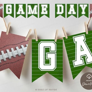 Może przedstawiać: Świąteczny baner "Game Day" z motywami piłki nożnej i proporczyków. Baner zawiera zielone proporczyki z białymi literami i grafiką piłki nożnej, zawieszone na sznurku za pomocą drewnianych spinaczy. Idealny na imprezę o tematyce piłkarskiej.