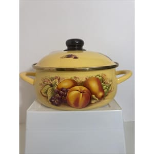 May include: A yellow enamel pot with a matching lid and two side handles. The exterior features a decorative illustration of peaches, grapes, and green leaves. The lid has a dark brown knob and a gold-toned metal rim around the top edge.