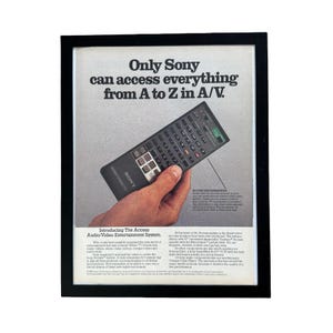Puede incluir: Un anuncio vintage enmarcado para el sistema de entretenimiento de audio y video Sony Access. El anuncio muestra un control remoto negro con numerosos botones y el texto Only Sony can access everything from A to Z in A/V en un marco negro.