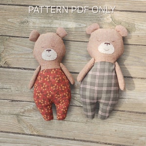 May include: Two brown teddy bear plush toys with different fabric patterns. One bear is wearing red pants with a floral pattern and the other bear is wearing plaid pants.