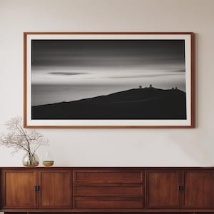 Puede incluir: Fotografía de paisaje en blanco y negro enmarcada de una cordillera con observatorios en la cima. La fotografía se muestra encima de un mueble de madera de estilo moderno con puertas y cajones.