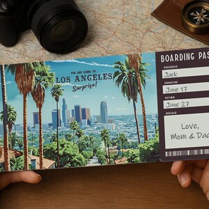 Puede incluir: Una tarjeta de embarque con una imagen del horizonte de Los Ángeles y palmeras. El texto en la tarjeta dice "You are going to Los Angeles Surprise!" y "Boarding Pass". El nombre del pasajero es "Jack" y la fecha de salida es el 17 de junio. La fecha de regreso es el 27 de junio. El mensaje dice "Love, Mom & Dad".