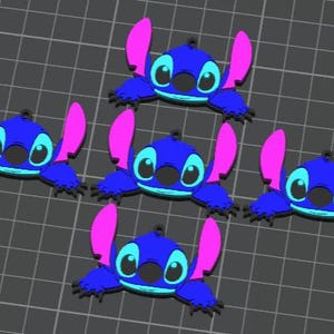 May include: A collection of five blue cartoon character charms with pink ears and black eyes. The charms are arranged on a gray grid background. The character has a round head and a small black nose.