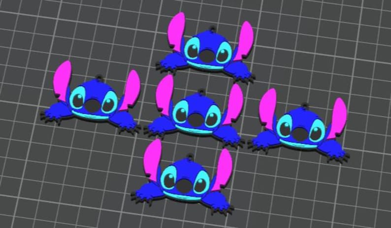 May include: A collection of five blue cartoon character charms with pink ears and black eyes. The charms are arranged on a gray grid background. The character has a round head and a small black nose.