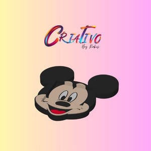 Op de afbeelding: Een cartoonafbeelding van Mickey Mouse met een glimlachende uitdrukking, zwarte oren en een rode mond. De afbeelding staat tegen een gradiëntachtergrond van geel, roze en paars. Het woord "Criativo" is in kleurrijk schrift geschreven.