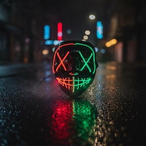 Peut inclure: Un masque noir doté de fils lumineux néon rouges et verts. Le motif comprend deux grands X sur les zones des yeux et une bouche cousue sur la partie inférieure, créant une expression faciale vibrante et illuminée dans l'obscurité.