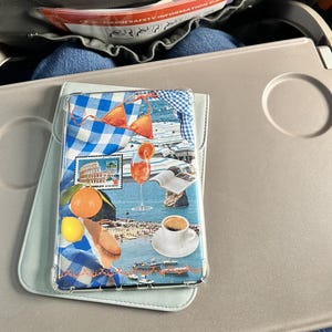 May include: A clear phone case with a collage design featuring a blue and white checked pattern, a red and orange bikini, a glass of orange juice, a book, a cup of coffee, and a view of a beach with people.