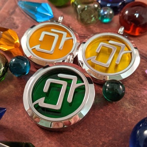 May include: Three silver-rimmed pendants with colorful centers, including yellow and green, are surrounded by glass beads and crystal shapes in various colors. The pendants feature a stylized design.