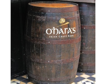 May include: A brown wooden barrel with a white label that says "O'Hara's Irish Craft Beer". The barrel is sitting on a black and white checkered floor.