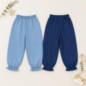 May include: Two pairs of pull-on pants made of denim fabric. One pair is light blue and the other is dark blue. Both pairs feature an elasticized waistband and gathered, ruffled cuffs at the bottom of each leg, creating a tapered silhouette.