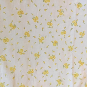 Peut inclure: Un tissu blanc orn&eacute; d'un motif r&eacute;p&eacute;titif de petites grappes de roses jaunes avec des tiges et des feuilles vert clair. L'imprim&eacute; floral est uniform&eacute;ment r&eacute;parti sur toute la surface, cr&eacute;ant une texture visuelle coh&eacute;rente et d&eacute;licate.