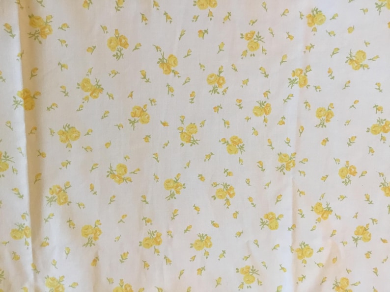 Peut inclure: Un tissu blanc orn&eacute; d'un motif r&eacute;p&eacute;titif de petites grappes de roses jaunes avec des tiges et des feuilles vert clair. L'imprim&eacute; floral est uniform&eacute;ment r&eacute;parti sur toute la surface, cr&eacute;ant une texture visuelle coh&eacute;rente et d&eacute;licate.