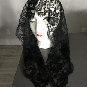May include: Black lace mantilla with a floral pattern. The lace is delicate and intricate.