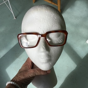 May include: A white styrofoam mannequin head with brown tortoiseshell glasses.