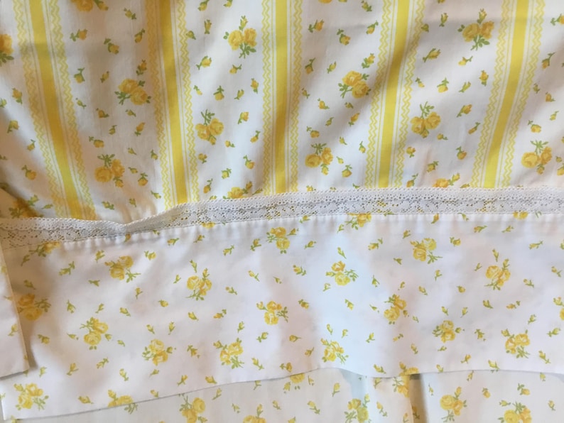 Peut inclure: Un tissu blanc orn&eacute; d'un motif de petites roses jaunes et de rayures verticales jaunes. Une bande horizontale de dentelle blanche s&eacute;pare la section ray&eacute;e d'une partie inf&eacute;rieure d&eacute;cor&eacute;e d'un imprim&eacute; floral jaune dispers&eacute;.